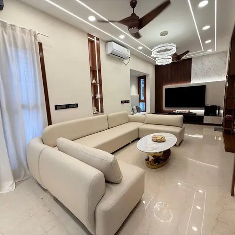 Living room with a large cream sectional sofa, a marble and gold coffee table, and a TV feature wall in marble cladding and wood fluted panelling beneath a