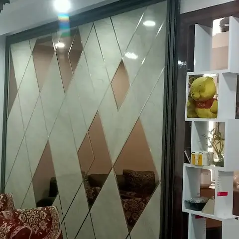 Living room with a large diamond-patterned mirrored partition wall, a red paisley-print sofa, and a white cube display shelf styled with curios
