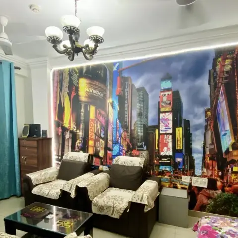 Living room with a large illuminated Times Square cityscape wall mural behind a wood sofa set with floral loose covers