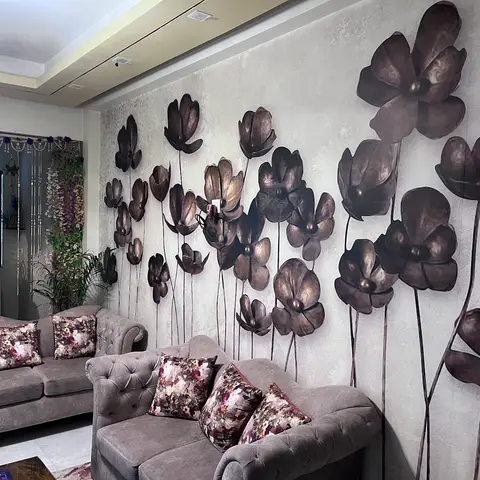 Living room with a large-scale bronze 3D floral mural covering the textured accent wall, grey tufted sofas with burgundy floral cushions
