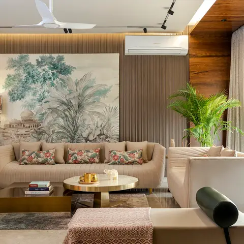 Living room with a large scenic mural of an Indian palace and palms above channel-tufted cream sofas, brass-and-marble coffee tables