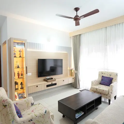 Living room with a light-wood TV wall unit and lit display cabinet, floral-print armchairs and a dark wood coffee table