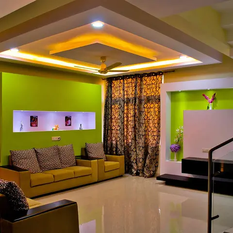 Living room with a lime-green feature wall and stepped cove-lit POP ceiling, backlit display niches holding photo frames