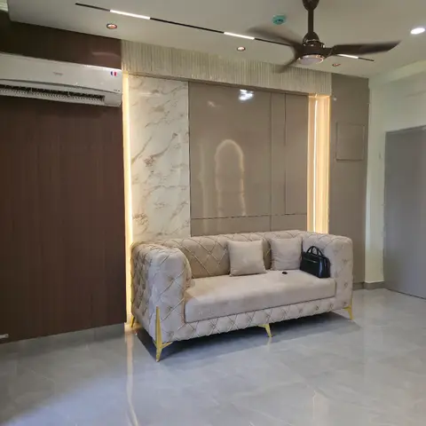 Living room with a marble-and-glossy-panel backlit feature wall behind a tufted beige sofa with brass legs.