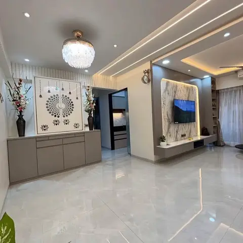 Living room with a marble-clad TV feature wall and floating console, and a taupe cabinet with laser-cut lotus-and-bell jaali doors