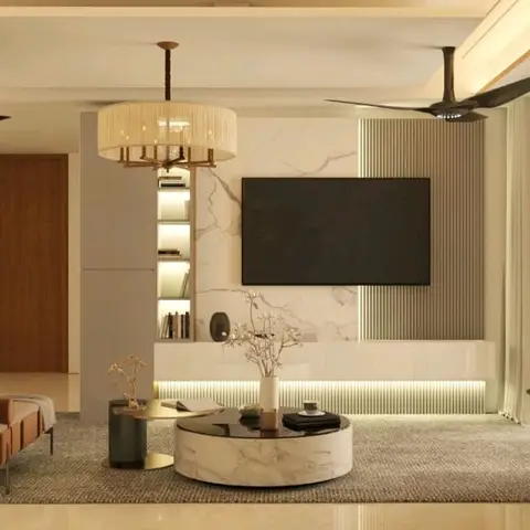 Living room with a marble-clad TV feature wall backed by fluted wood panelling, a drum-shade pendant chandelier, and a round marble coffee table on a jute rug.