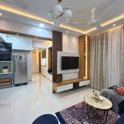 Living room with a marble-clad TV unit flanked by a fluted wood pillar and open display shelving, a navy sofa