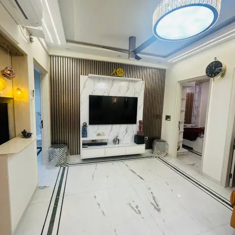 Living room with a marble-clad TV wall framed by fluted gold-and-black metallic panelling, a round crystal drum chandelier