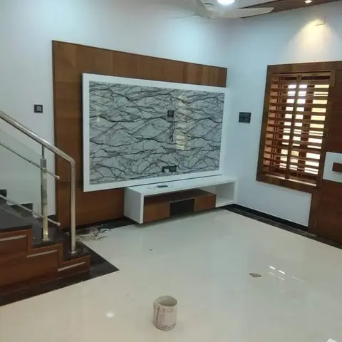 Living room with a marble-panel TV feature wall bordered in walnut wood cladding, a white floating TV console, a glass-railed staircase to the side