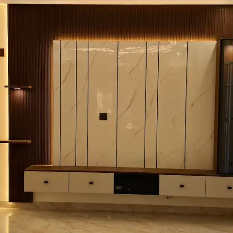 Living room with a marble-slab TV wall flanked by dark fluted wood panelling, a backlit niche with a wooden cross