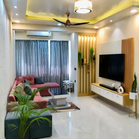Living room with a maroon L-shaped sofa, wood-slat TV feature wall and gold cove-lit ceiling