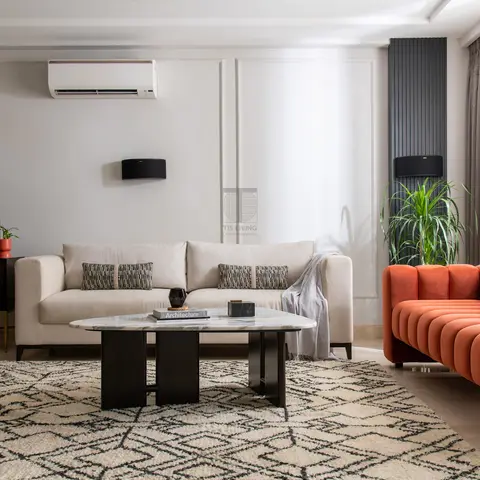 Living room with a moulded panel wall, a beige sofa paired with a burnt-orange channel-tufted sofa