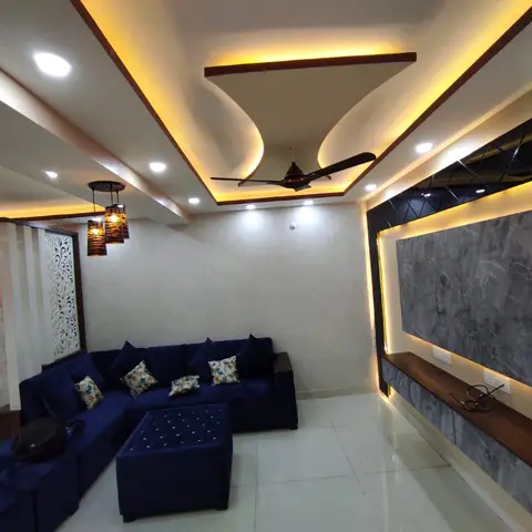 Living room with a multi-tier curved cove-lit POP ceiling around the fan, a navy tufted sectional sofa