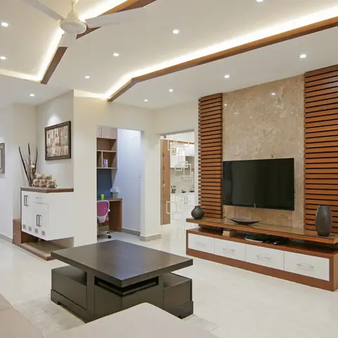 Living room with a multi-tier cove-lit false ceiling and a marble-and-wood-slat TV feature wall over a floating console