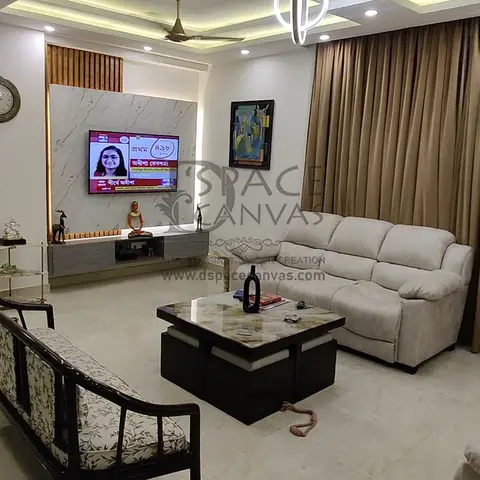 Living room with a multi-tier cove-lit false ceiling, a marble-panel TV wall with fluted wood accent, a beige reclining sofa, a carved wooden bench