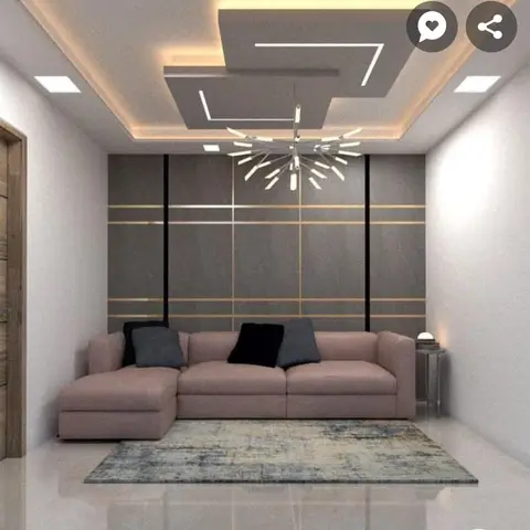 Living room with a multi-tier cove-lit false ceiling, a sputnik chandelier and a grey wall panel with brass strip inlay behind a blush sectional sofa
