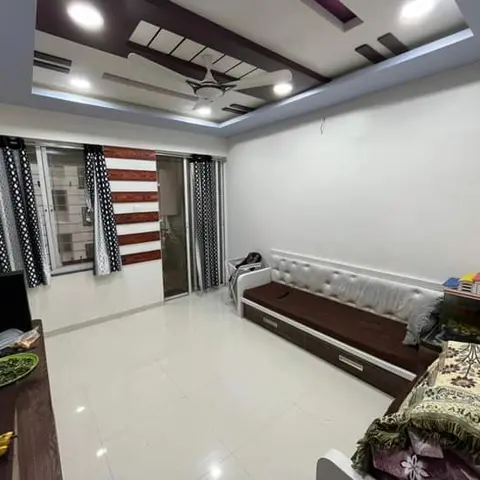 Living room with a multi-tier maroon-and-white POP false ceiling with cove lighting, a brown tufted sofa-cum-bed