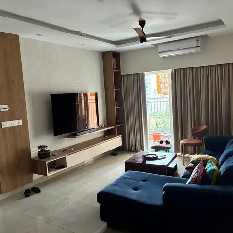 Living room with a navy blue L-shaped sofa and patterned cushions facing a wood-and-textured-wallpaper TV wall with a floating console.