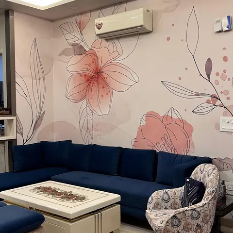 Living room with a navy velvet L-shaped sofa set against a hand-illustrated floral wallpaper mural, cove-lit false ceiling, and a patterned ikat accent chair.