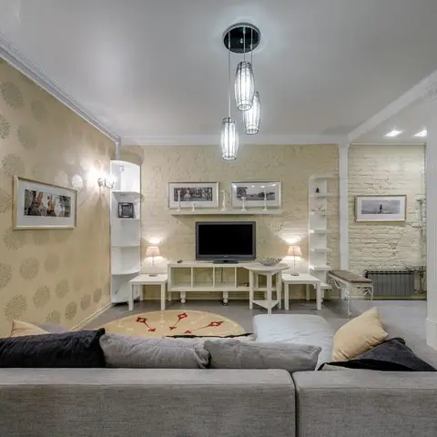Living room with a painted brick accent wall, floral wallpaper, a glass cluster pendant light, a white TV console with corner shelving