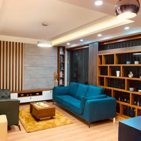 Living room with a peacock-blue velvet sofa facing a dark green tufted leather armchair across a mustard shag rug