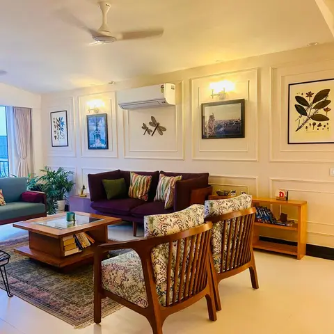 Living room with a plum velvet sofa and patterned wood-frame armchairs around a wood coffee table