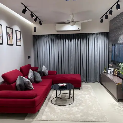 Living room with a red velvet L-shaped sectional sofa, a chevron-pattern wallpaper accent wall behind the TV