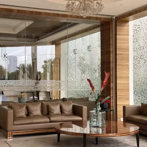 Living room with a round high-gloss wood coffee table, tan leather sofas, a crystal chandelier in a circular pop ceiling