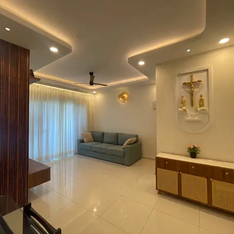 Living room with a stepped cove-lit false ceiling, a sage green sofa facing sheer curtains, a fluted wood partition wall