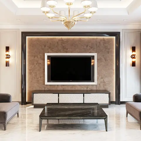 Living room with a stone-clad, cove-lit TV feature wall framed in glossy black trim, a gold chandelier, marble flooring, and matching grey velvet armchairs.