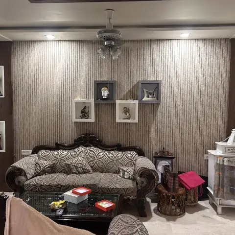 Living room with a striped wallpaper feature wall, framed curio niches displaying figurines, a carved wood-frame upholstered sofa