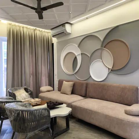 Living room with a taupe sectional sofa facing a sculptural wall of overlapping 3D painted rings