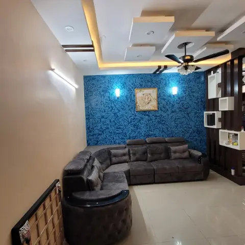 Living room with a textured blue wallpaper accent wall featuring a framed leopard print between two wall sconces, a grey tufted L-shaped sofa