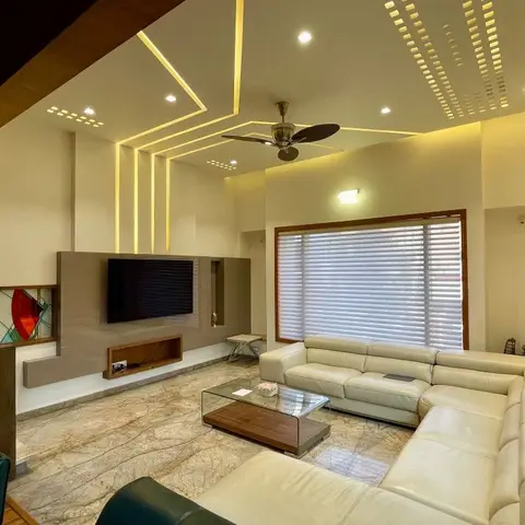 Living room with a tiered cove-lit POP ceiling over a floating TV console and a cream leather L-shaped sofa around a glass-top coffee table.