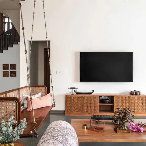 Living room with a traditional wooden hanging swing with cane backrest, a fretwork-front wood TV console, and a coffered white ceiling