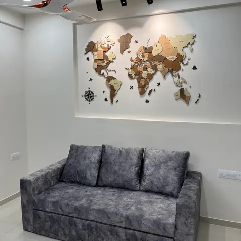 Living room with a tufted charcoal-grey sofa beneath a recessed wall niche featuring a wood-inlay world map art piece, lit by track spotlights.