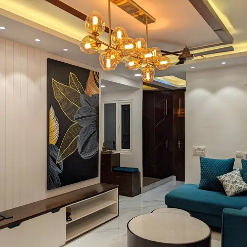 Living room with a vertical white panelled TV wall, oversized black-and-gold botanical artwork, a sculptural gold bubble chandelier