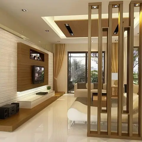 Living room with a vertical wood-slat partition screen dividing the TV wall from a sofa seating area, white textured tile behind a floating wood TV console