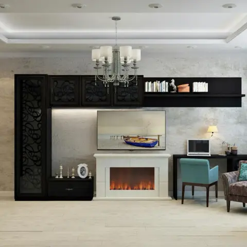 Living room with a wall-mounted TV above a stone-clad electric fireplace, flanked by a dark fretwork-front cabinet and a small study nook with a teal chair