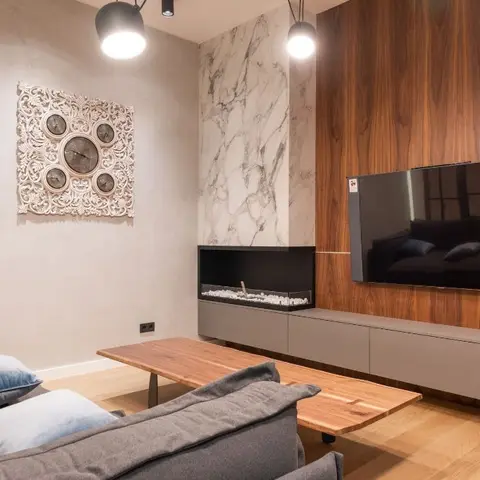 Living room with a walnut veneer TV wall recessed with a built-in linear fireplace niche framed in book-matched marble, a low grey media console
