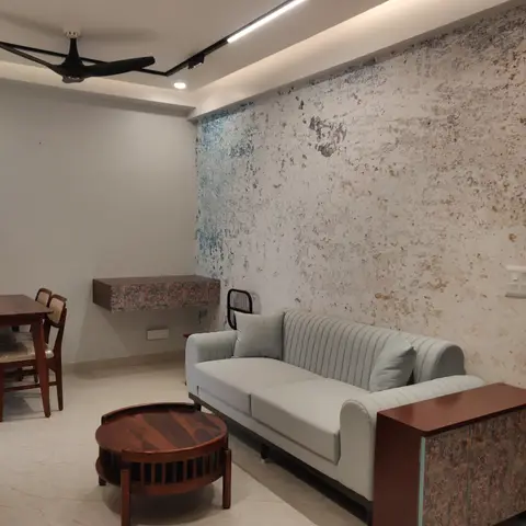 Living room with a weathered white-and-blue distressed-plaster accent wall, a channel-tufted pale sofa