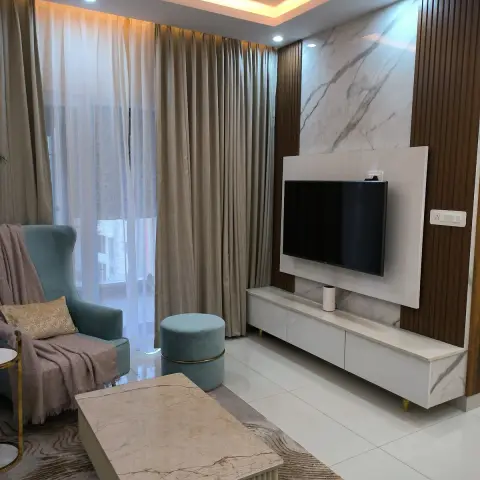 Living room with a white marble TV panel flanked by teak fluted strips, a marble-topped console on slim brass legs
