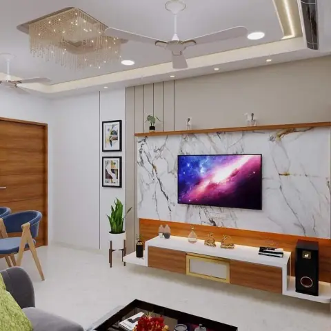Living room with a white marble-look TV panel framed by teak trims and a slim shelf of brass figurines, a two-tone floating console below
