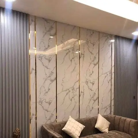 Living room with a white marble accent wall featuring gold inlay strips, flanked by grey fluted panelling, behind a channel-tufted taupe sofa.