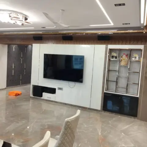 Living room with a white marble-clad TV feature wall, a mirrored chevron accent wall, a glass display shelf with a laughing Buddha figurine