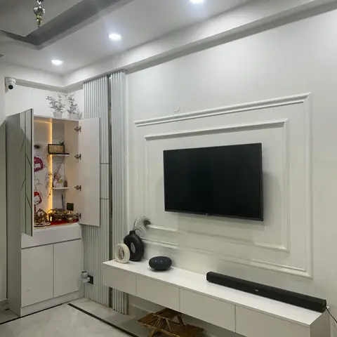 Living room with a white raised-moulding TV feature wall, a floating console with a soundbar and ceramic vases