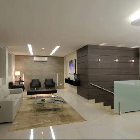 Living room with a white sofa, black leather armchairs and a glass coffee table on a beige rug, set against a stone-clad accent wall with wall sconces