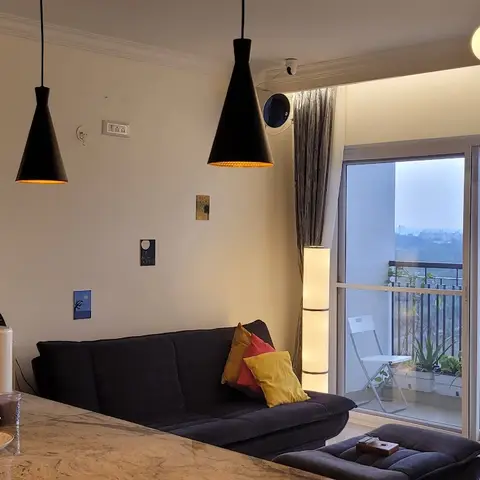Living room with a wood-and-glass crockery display unit, black cone pendant lights over a breakfast counter