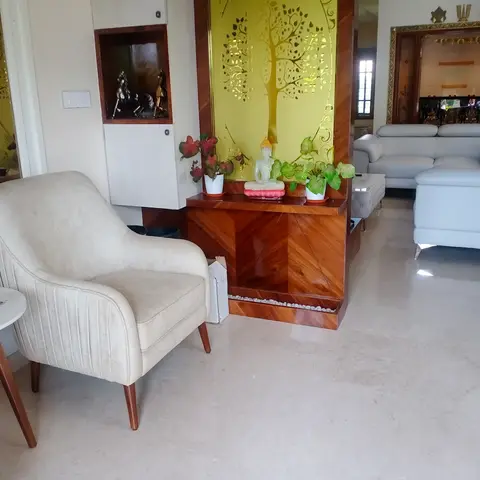 Living room with a wood console divider featuring an etched golden tree mirror panel, a cream tufted armchair