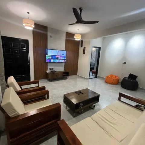 Living room with a wood-frame sofa set in cream upholstery, a wood-panelled TV wall with a floating console